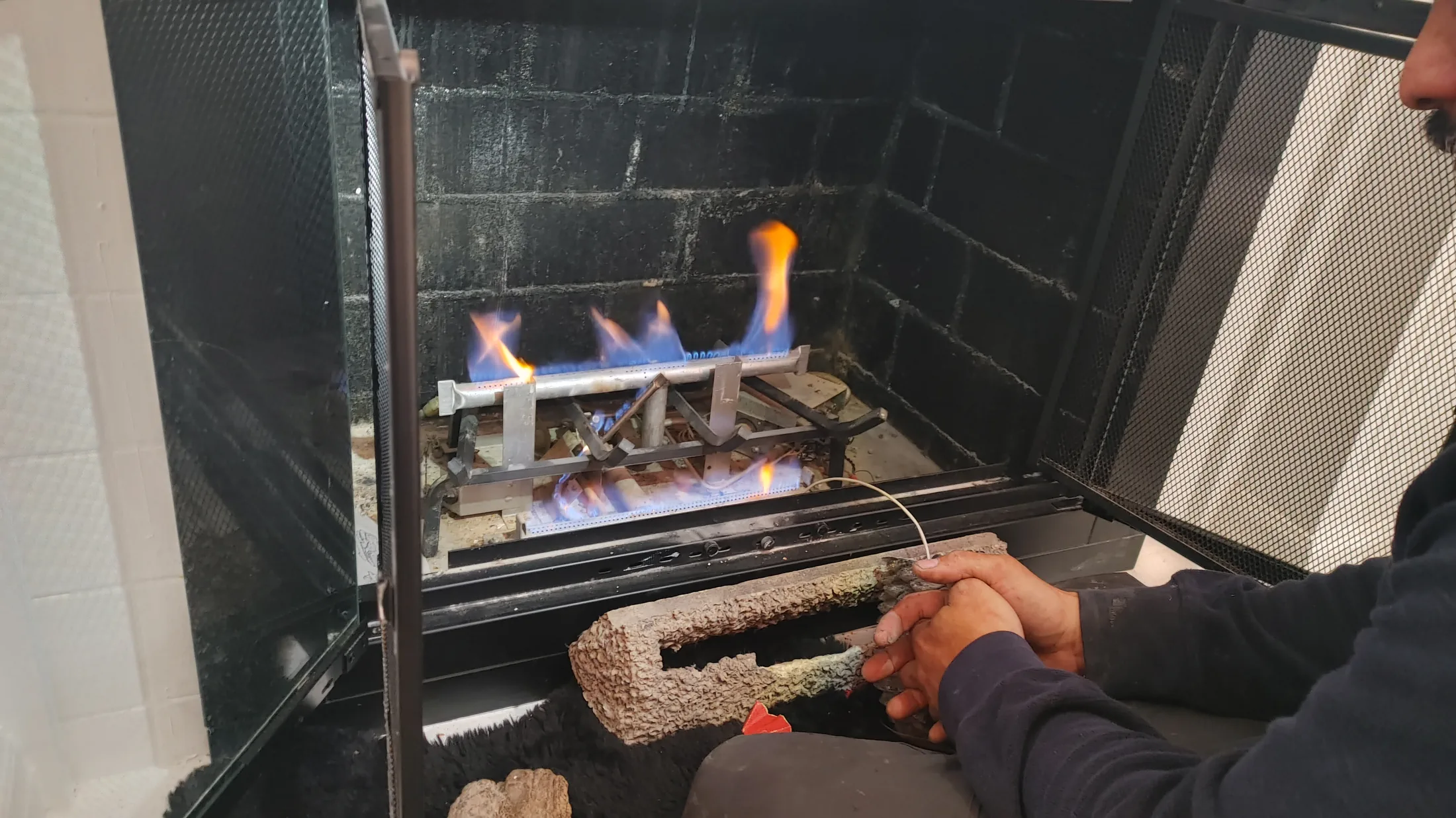 Technician testing a lit gas fireplace as part of a safety check